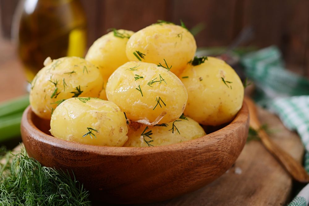 En skål med kokt potatis med dill på.