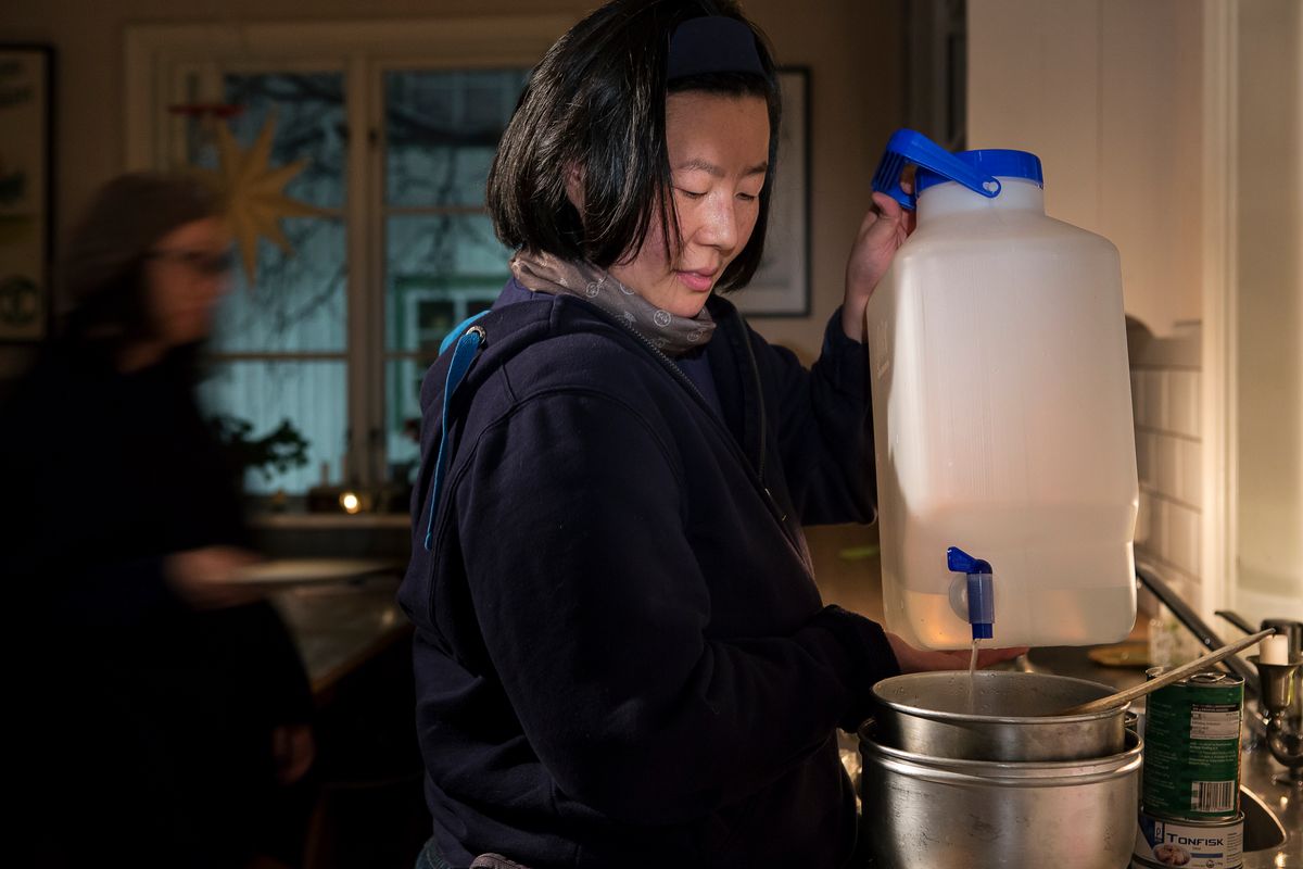 Köksmiljö där en person fyller kastrull från plastdunk