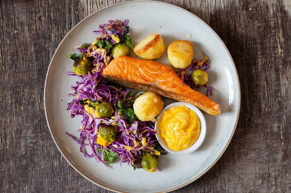 Lax, rostad potatis och coleslaw på tallrik med saffransaioli i liten skål.