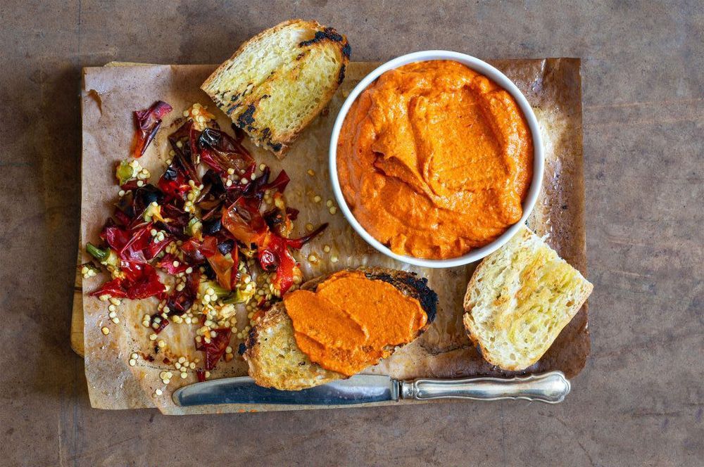 Salsa romesco i skål på bricka med bröd.