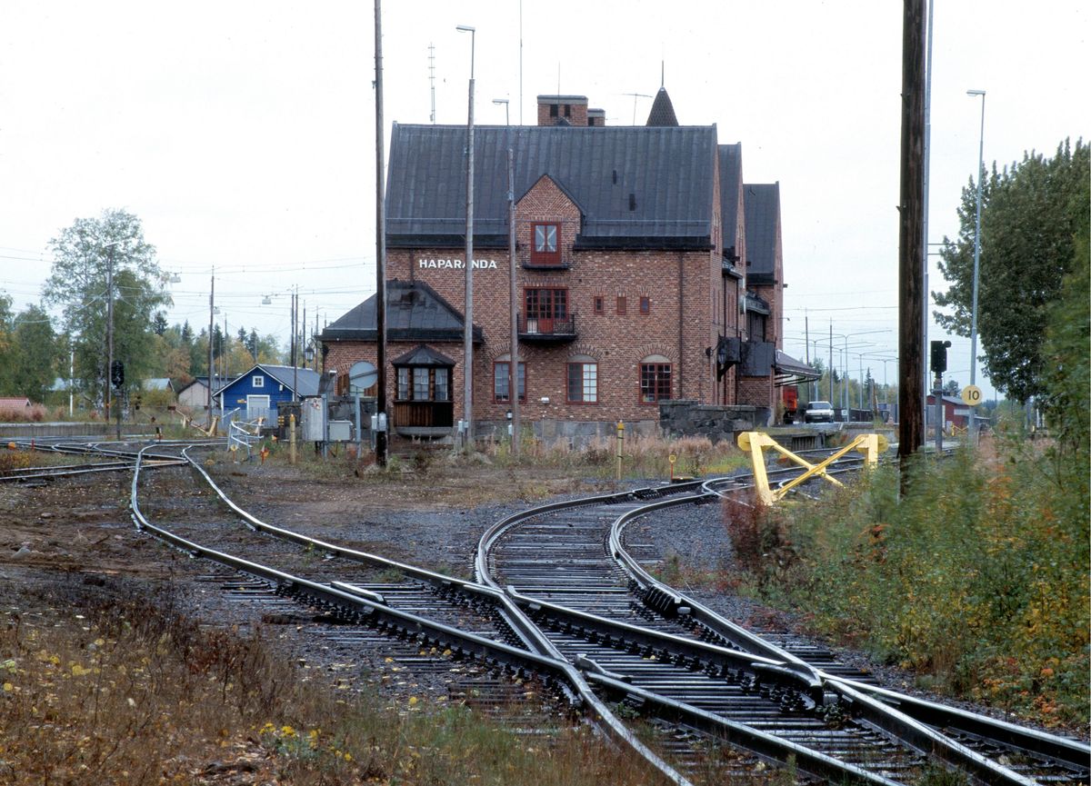 Järnvägsspår som delar sig framför en röd tegelstation i Haparanda