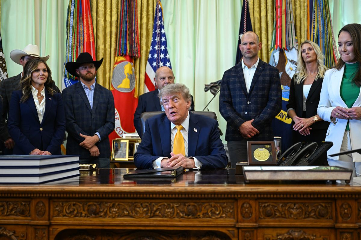 President Donald Trump sitter vid skrivbord i Ovala rummet omgiven av flera personer