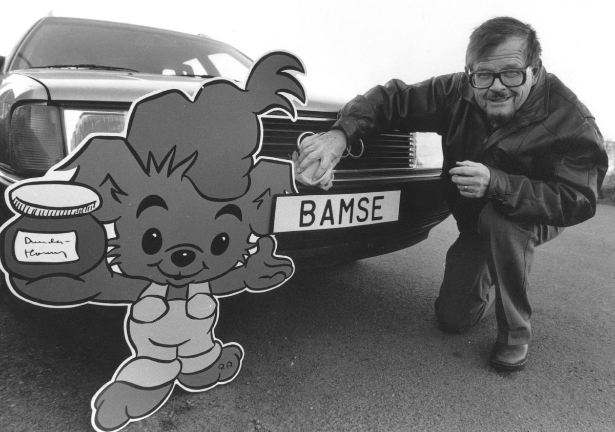 Fotomontage med tecknaren Rune Andréasson och seriefiguren Bamse framför bil med texten Bamse på nummerskylten.