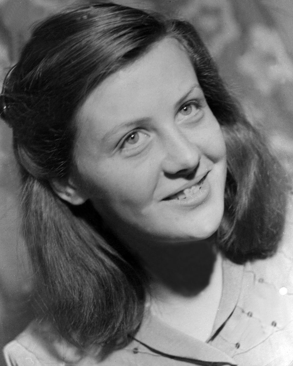 Ung Ellinor Taube ler i ett svartvitt porträttfoto, lätt vänd uppåt åt sidan