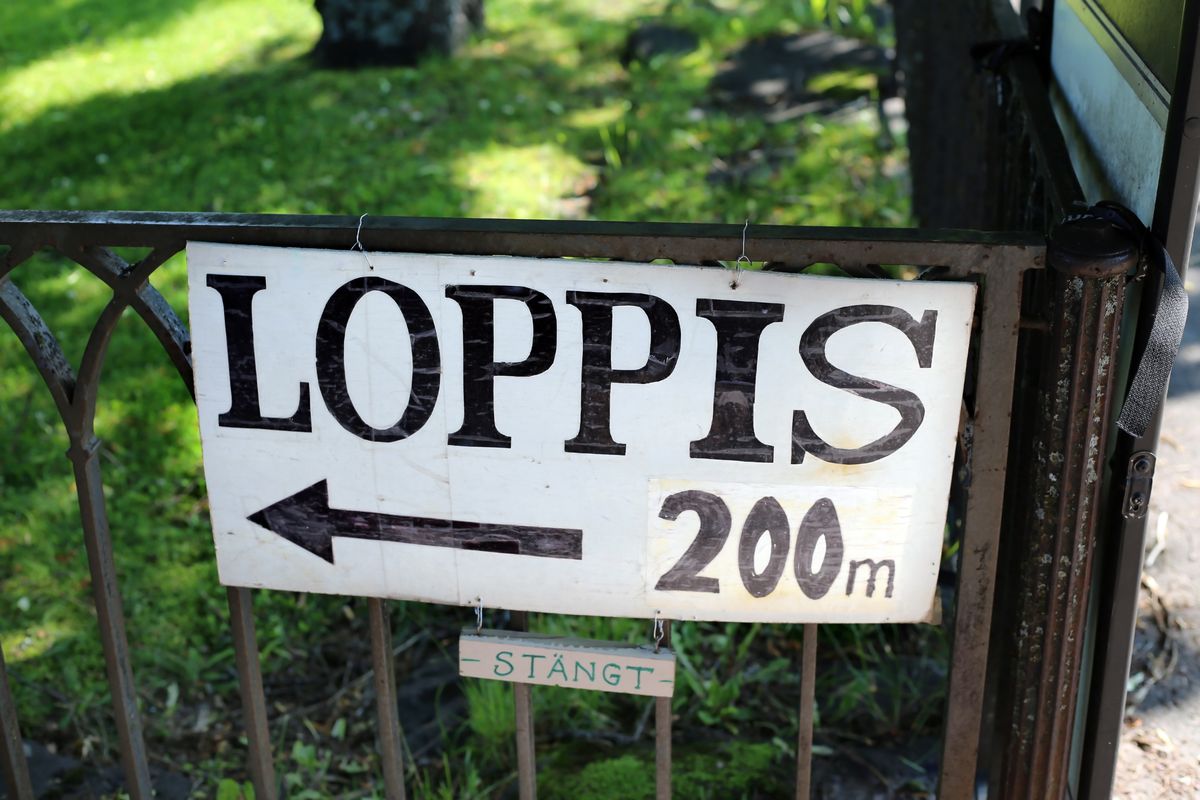 Loppisfynd. Skylt på grind med texten 'Loppis 200 m' och en pil åt vänster, mindre skylt 'Stängt'.