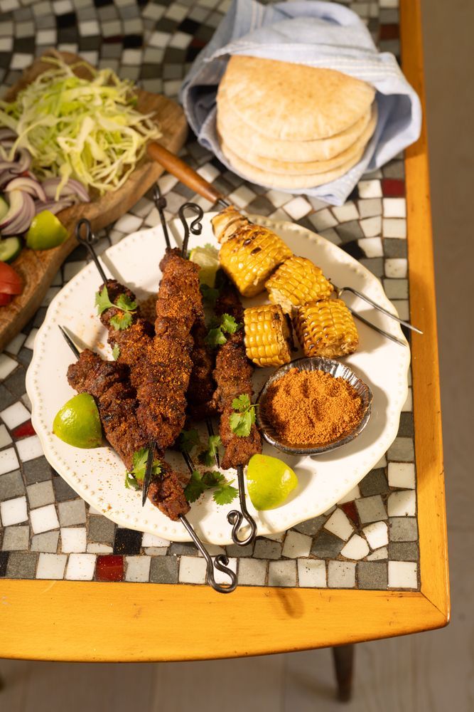 Suya – kryddig ryggbiff – på fat med majskolvar.