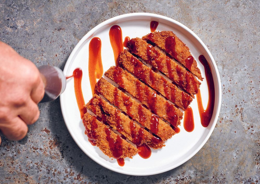 Stekt tonkatsu med sås på tallrik.